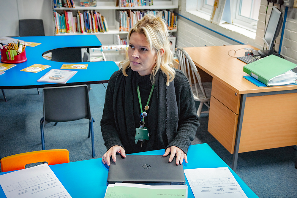 A teacher sat a desk in an empty classroom trying to lesson plan