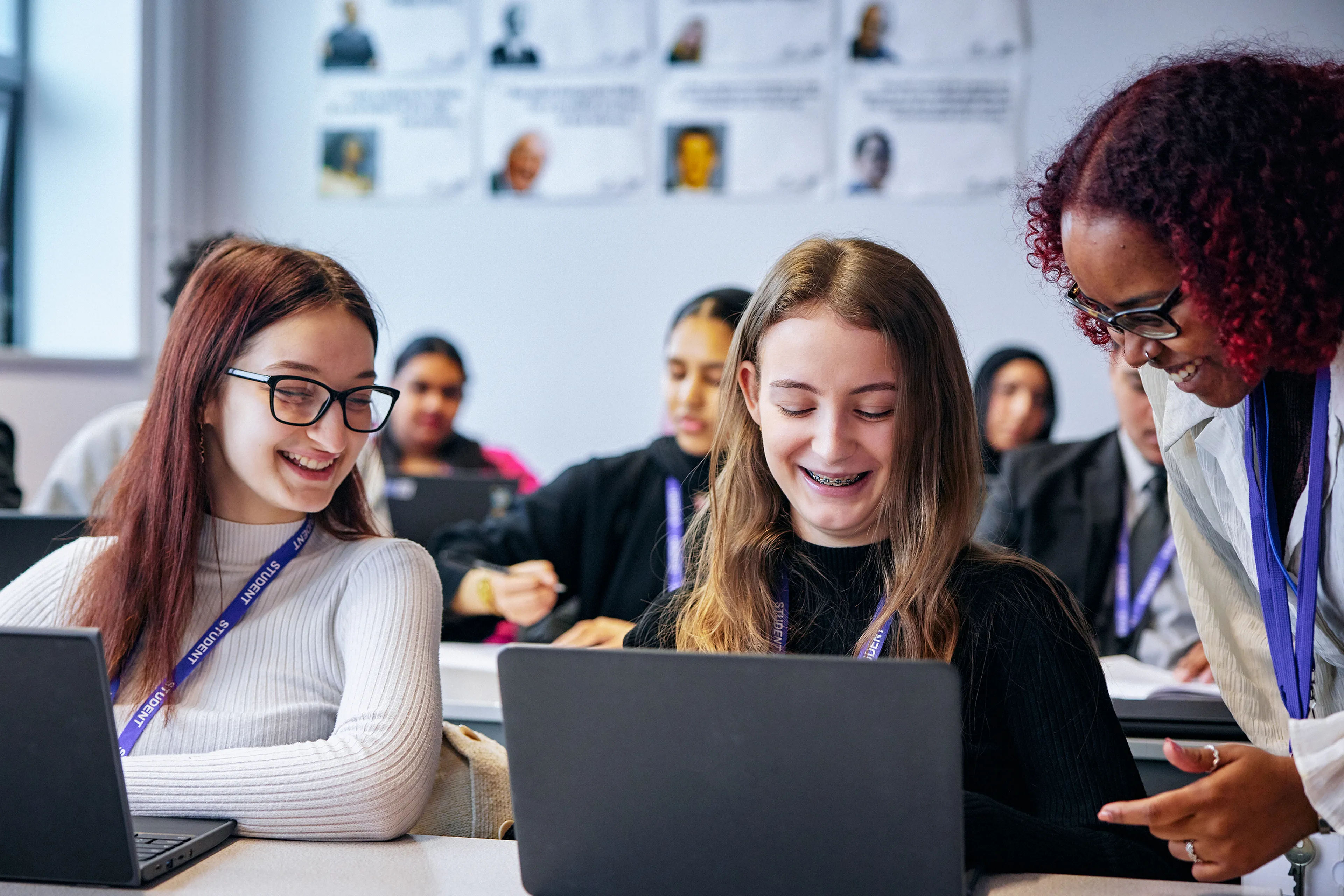 A teacher interacting with two pupils using laptops
