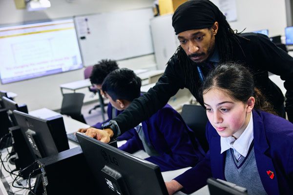 A teacher showing a student on a computer how to do something